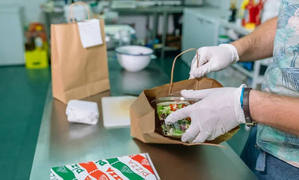 Cocinero irreconocible empacando una orden de comida para llevar —  Fotos de Stock