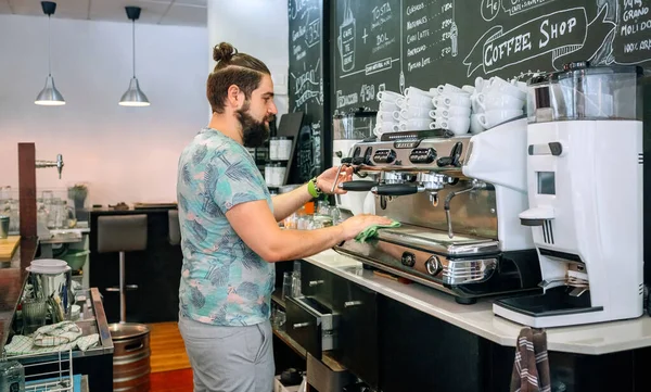 Garçom jovem limpando a máquina de café — Fotografia de Stock