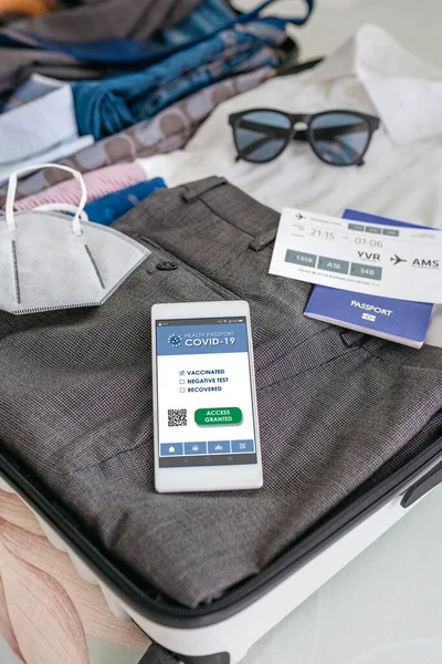 Valise d'homme d'affaires préparée pour un voyage d'affaires avec passeport covid sur mobile — Photo