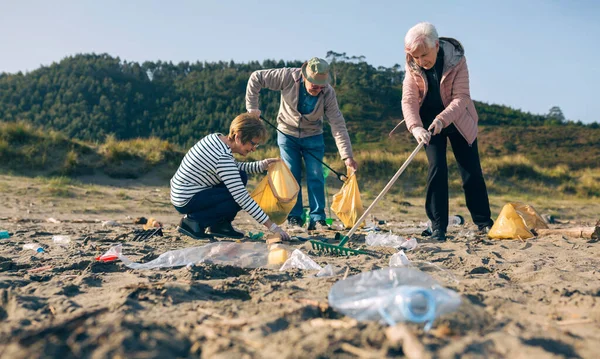 Voluntarios mayores limpiando la playa — Foto de Stock