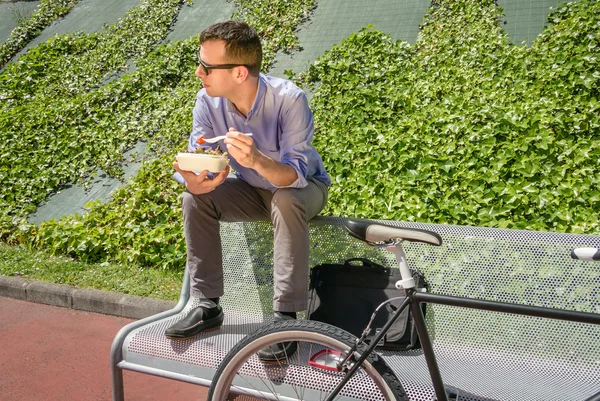 Young business man eating at lunch break outdoors — Stock Photo, Image