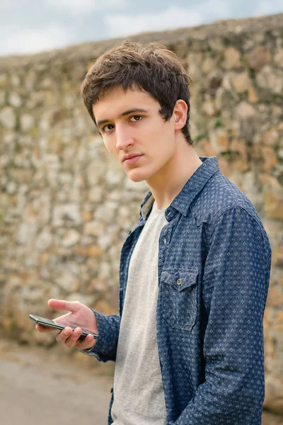 Hipster nastolatek za pomocą inteligentnego telefonu na zewnątrz — Zdjęcie stockowe