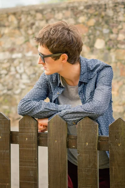 Хипстерский подросток в солнечных очках через забор — стоковое фото