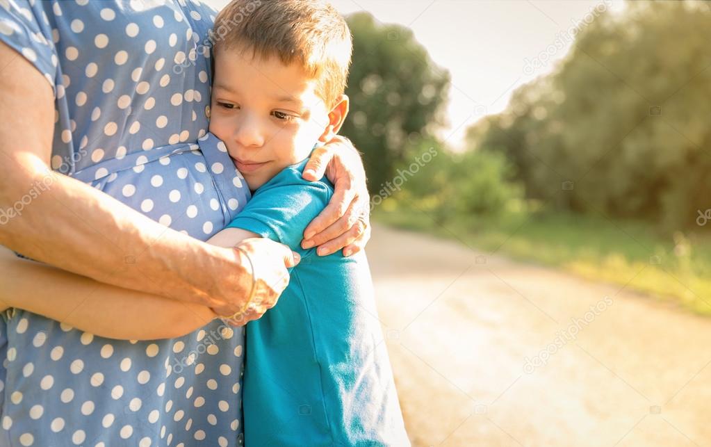 Grandson hugging to his grandmother outdoors