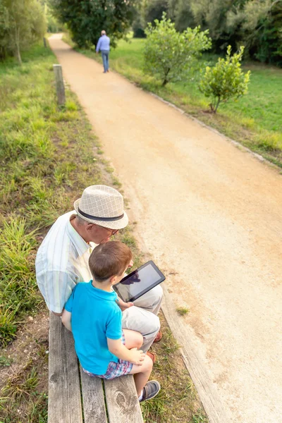 Grandchild and grandfather using a tablet outdoors — Stock Photo, Image
