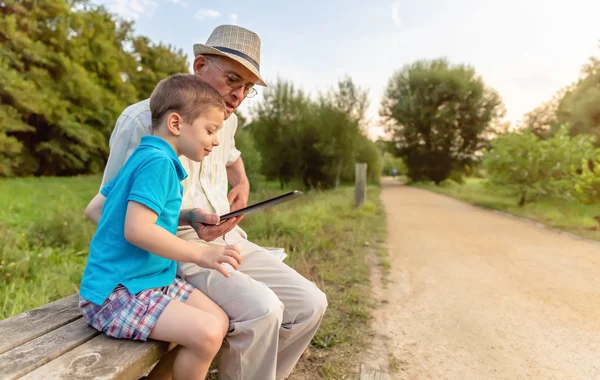 Torun ve büyükbabası açık havada tablet kullanma — Stok fotoğraf