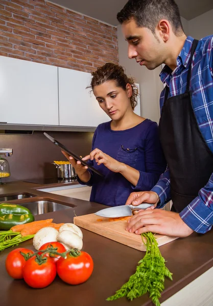 Paar in huis keuken op zoek recept met een elektronische tablet — Stockfoto