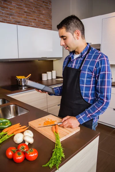 Чоловік на домашній кухні шукає рецепт з електронним планшетом — стокове фото