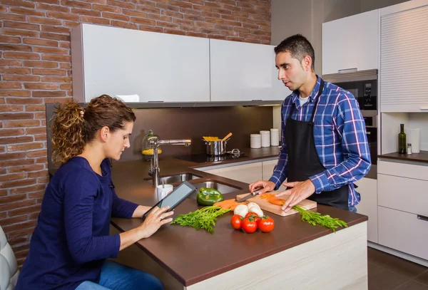 Мужчина приготовления пищи и женщина ищет рецепт в электронной таблетке — стоковое фото