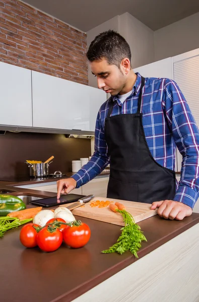 Man in huis keuken op zoek recept met een elektronische tablet — Stockfoto