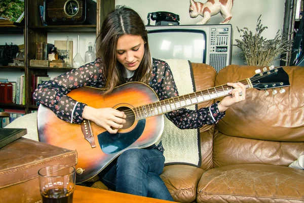 Giovane ragazza hipster suonare la chitarra acustica a casa — Foto Stock