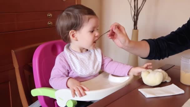 Menina feliz bebê comendo com uma colher de comida — Vídeo de Stock