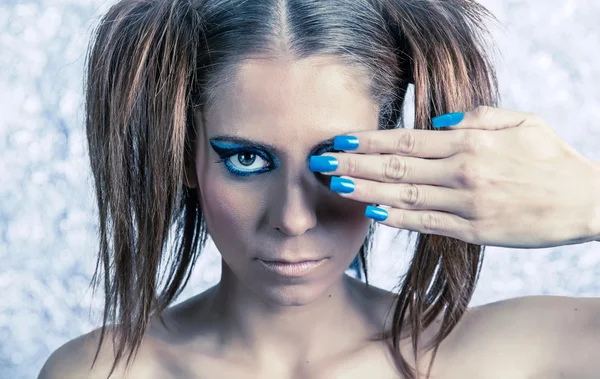 Beautiful model with pigtails, fancy makeup and blue manicure