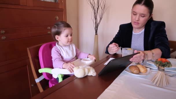 Happy baby girl eating and watching electronic tablet — Stock Video
