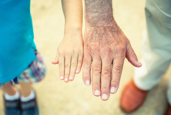 Bambino e uomo anziano confrontando le sue dimensioni delle mani — Foto Stock