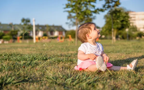 Bir çim parkın oturup iskambil kız mutlu bebek — Stok fotoğraf