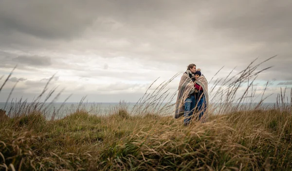 Молода пара обіймається на відкритому повітрі під ковдрою в холодний день — стокове фото