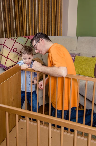 Vater und Sohn montieren Gitterbett für Neugeborenes zu Hause — Stockfoto