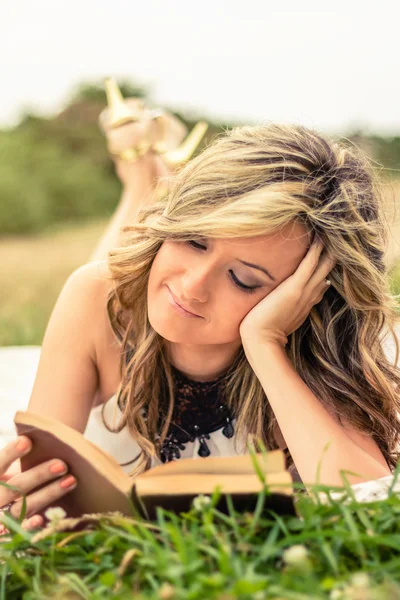 Romantisk flicka läsa en bok liggande utomhus — Stockfoto