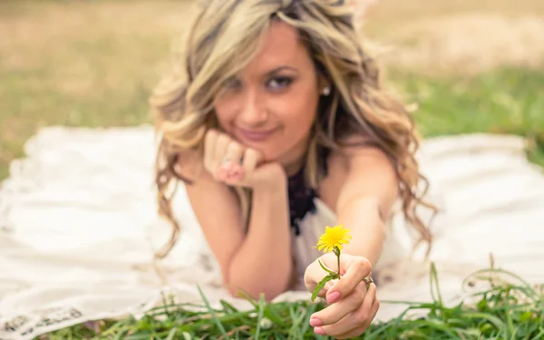 Romantic girl holding flower in the hand lying down outdoors — Stock Photo, Image