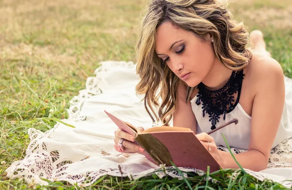 Romantisk flicka skriver i en dagbok liggande utomhus — Stockfoto