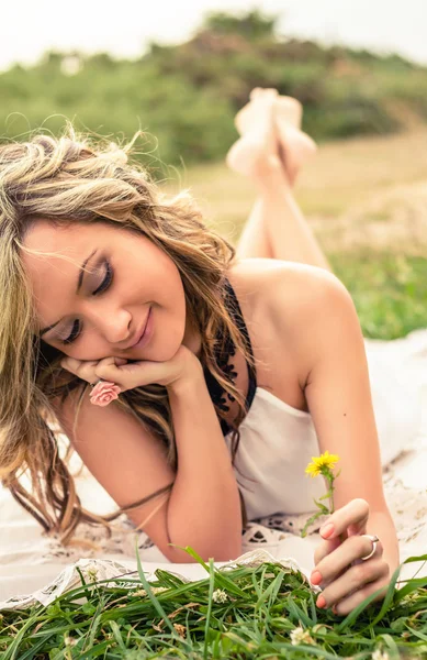Menina romântica com flor na mão deitada ao ar livre — Fotografia de Stock