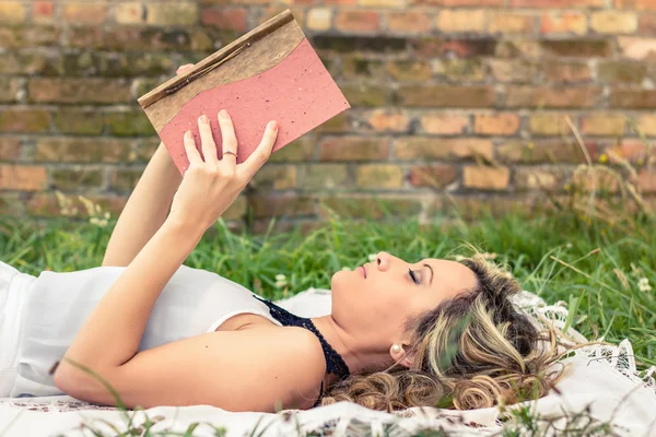 Fille romantique lisant un livre couché à l'extérieur — Photo