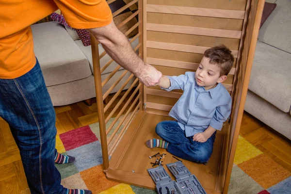 Son and father assembling cot for a newborn at home — Stock Photo, Image