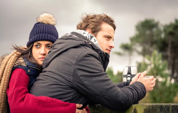 Pareja joven abrazando y tomando bebidas calientes al aire libre — Foto de Stock