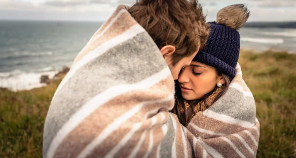 Young couple embracing outdoors under blanket in a cold day — Stock Photo, Image