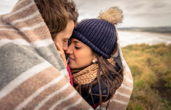 Jovem casal abraçando ao ar livre sob cobertor em um dia frio — Fotografia de Stock