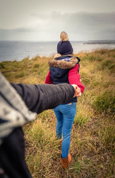 男の手を握って、牧草地を引いて若い女性 — ストック写真