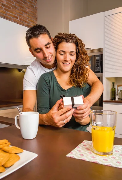 Man embracing and giving a gift box to his surprised girlfriend — Stock Photo, Image