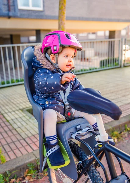 Petite fille avec casque sur la tête assis dans le siège de vélo — Photo