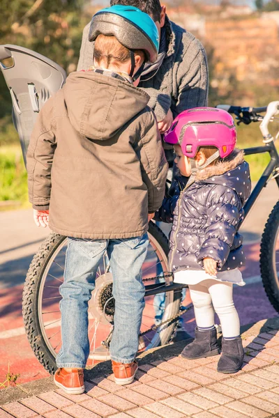 子供たちに自転車のタイヤを修理しながら父親を見て — ストック写真