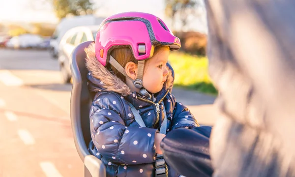 Menina com capacete na cabeça sentado no assento da bicicleta — Fotografia de Stock