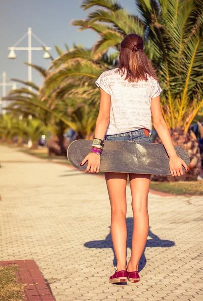 Visão traseira da menina com um skate ao ar livre no verão — Fotografia de Stock