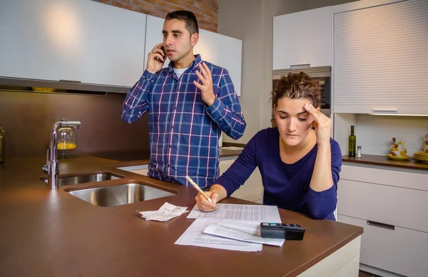 Homme en colère argumentant au téléphone tandis que la femme de calculer des lignes de crédit — Photo