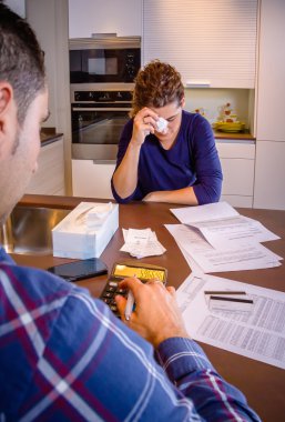 Unemployed husband reviewing the bills and wife crying by debts clipart