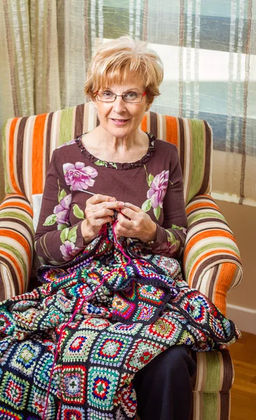 Старшая женщина вязала шерстяное одеяло с заплатами — стоковое фото
