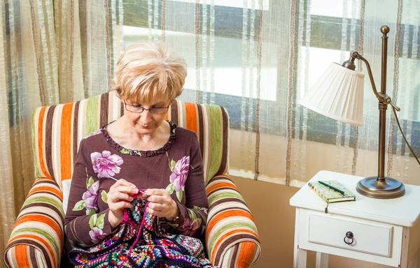 Äldre kvinna stickning en ull täcke med fläckar — Stockfoto