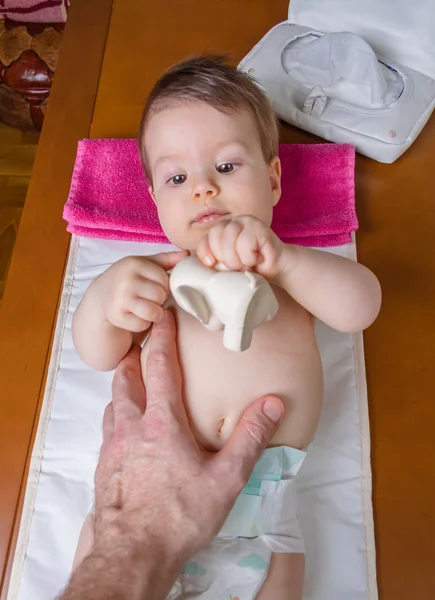 Barnet ligger leker med en leksak gummi — Stockfoto