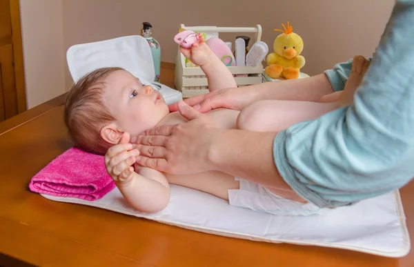 Mother massaging body of her baby lying — Stock Photo, Image