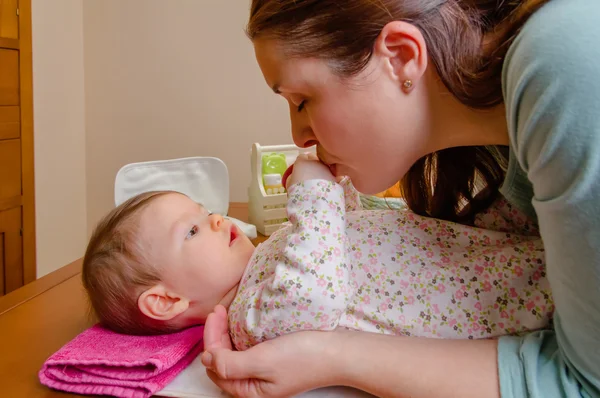 Mother kissing hands of her baby lying — Stock Photo, Image