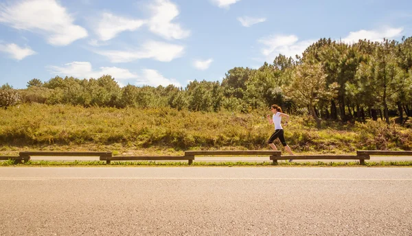 Молодая женщина в спортивной одежде бежит по взлетно-посадочной полосе — стоковое фото