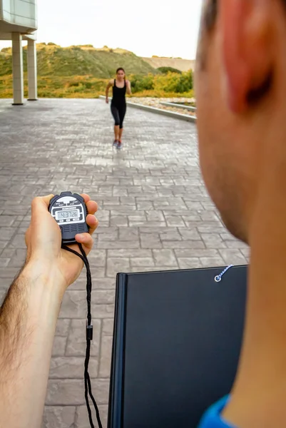 Entrenador mano usando cronómetro para el entrenamiento de la mujer de tiempo — Foto de Stock