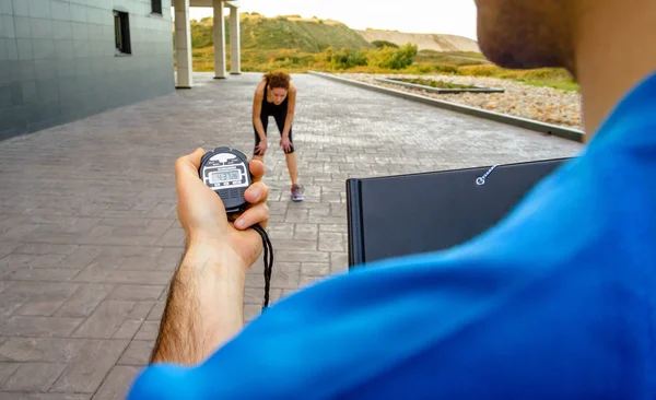 Entrenador mano usando cronómetro para el entrenamiento de la mujer de tiempo — Foto de Stock