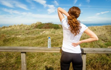 Athletic woman touching neck and back muscles by injury