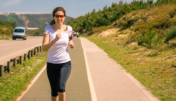 Mujer joven con auriculares escuchando música y corriendo — Foto de Stock