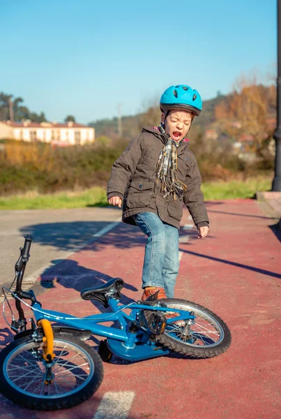 Naughty boy screaming and kicking his bike on ground — Stock Photo, Image